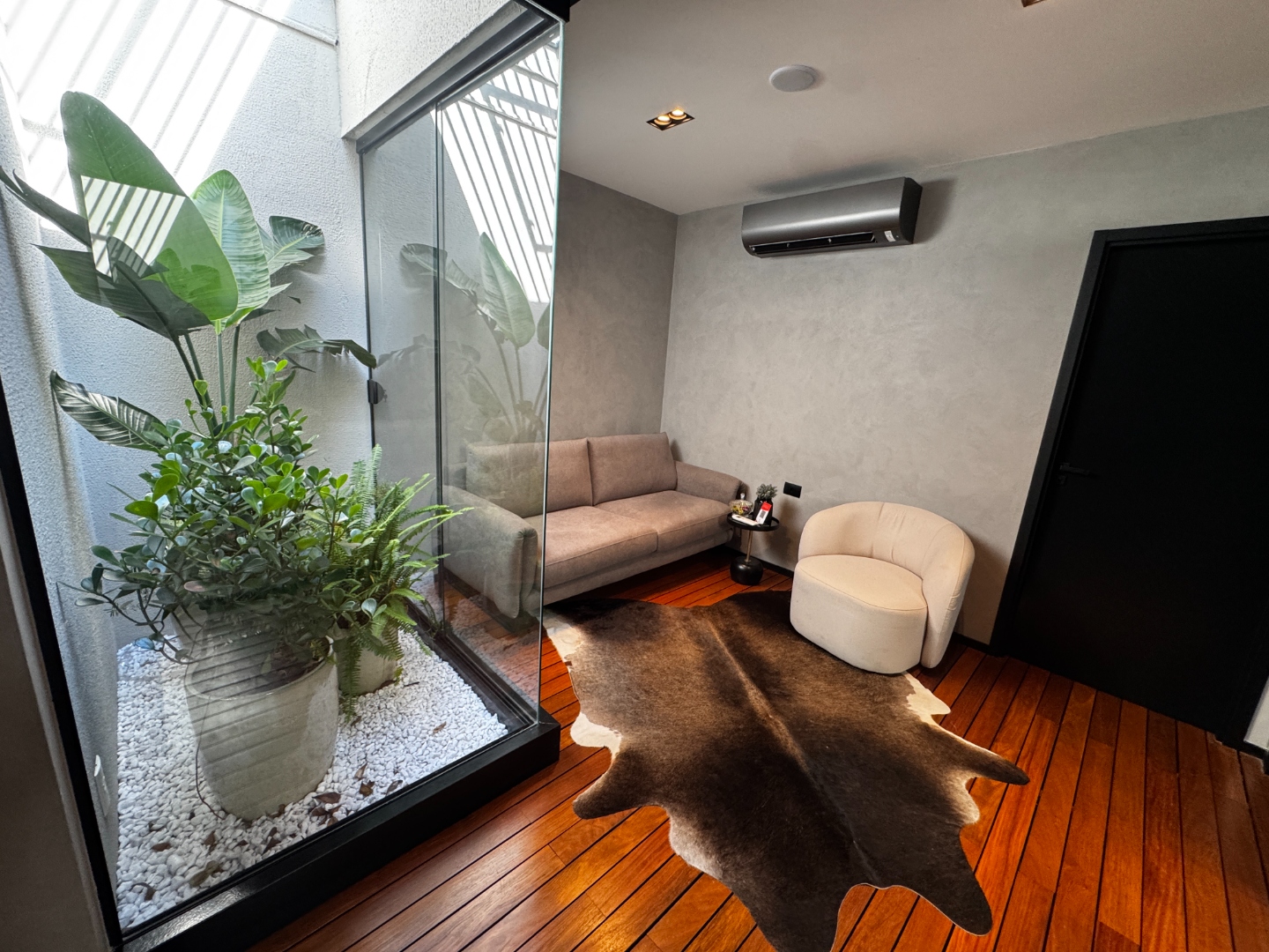 Sala de espera com jardim — piso de madeira e parede de vidro com plantas